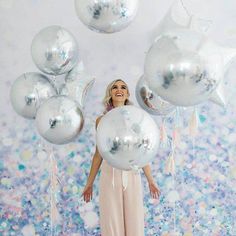 a woman standing in front of balloons and confetti