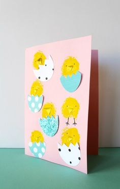 a pink card with yellow chicks and blue polka dots on the front, sitting on a green surface