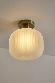 a ceiling light with a white glass shade hanging from the ceiling in an empty room