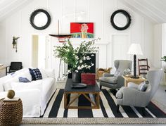 a living room filled with white furniture and lots of mirrors on the wall above it