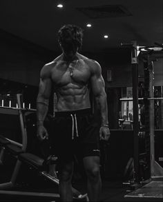 a shirtless man standing in front of a gym machine