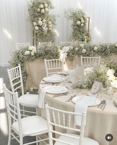 a table set up with white flowers and place settings