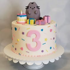 a birthday cake with a cat on top and candles in the shape of numbers 3