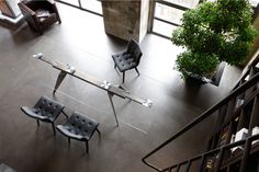 an overhead view of chairs and tables in a room with large windows, stairs and potted plants