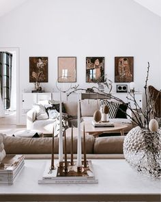 a living room filled with lots of furniture next to a white table and wall mounted pictures