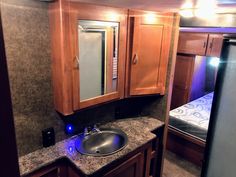 a bathroom with wooden cabinets and granite counter tops in a trailer or home built vehicle