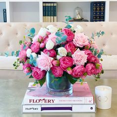 a vase filled with pink and white flowers sitting on top of a book