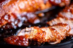 meat is being cooked on the grill with bbq sauce