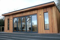 a small wooden building with glass doors on the outside and steps leading up to it