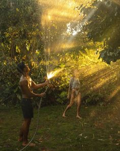 two men are spraying water on each other with hoses in the sunbeams