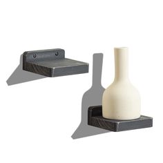 two black and white vases sitting next to each other on wooden shelves with brackets