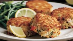 crab cakes with lemon wedges and greens on a plate