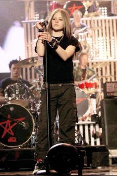 a woman standing on top of a stage holding a microphone in her hand and looking at the camera