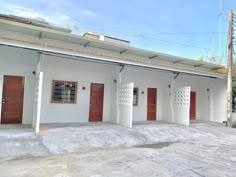 three white buildings with wooden doors and windows