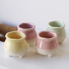 three small vases sitting on top of a white table next to a wooden spoon