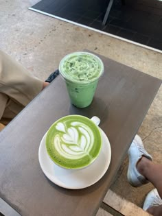 two cups of green tea sit next to each other on a table in a cafe