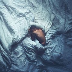 a man laying in bed with his head under the covers