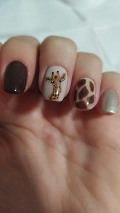 Hand with palm facing up and four nails bent over showing a dark brown on the index fingernail, a realistic hand painted giraffe face on a nude background on the middle nail.A giraffes fur pattern on the ringfinger nail and a shimmery champagne colour on the pinkyfingernail. The cuticles are clean and the glossy, overlay is smooth. African Safari Nails, Giraffe Nails Designs, Jungle Theme Nails, Nails Giraffe, Giraffe Print Nails, Zoo Nails, Giraffe Nail Art, Animal Print Nail Designs, Elephant Nails