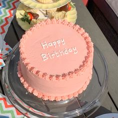 a pink birthday cake sitting on top of a glass plate