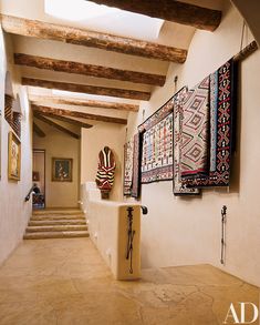 a hallway with art hanging on the wall and rugs hung up to the ceiling