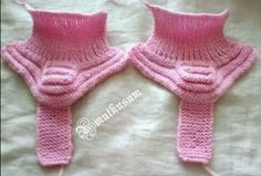 two pink knitted mittens sitting on top of a bed