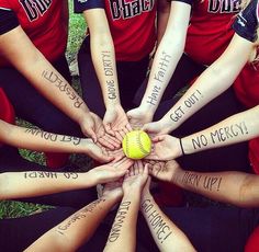 a group of girls in red shirts holding a ball with writing on their arms and hands