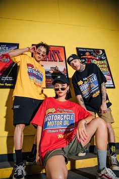 three people posing for a photo in front of a yellow wall with posters on it