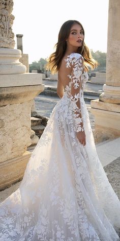 a woman in a wedding dress standing on the street with her back to the camera