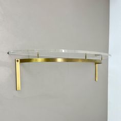 a glass shelf with gold metal brackets on the wall