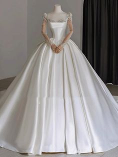 a white wedding dress with long sleeves on display in front of a mannequin