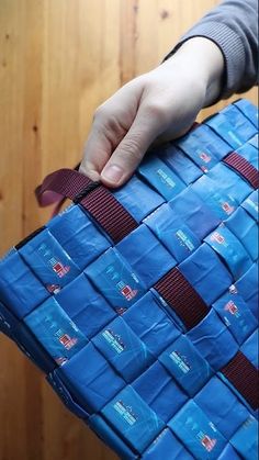 a person is holding a blue bag with red ribbons on it and the bottom part of the bag has been folded