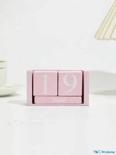 a pink wooden block with the number 19 on it and a lamp next to it