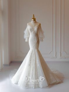 a wedding dress on display in front of a white wall