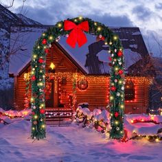 a house covered in snow with christmas lights on it's front door and an arch