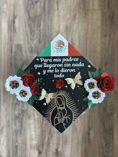 a graduation cap decorated with flowers on top of a wooden floor next to a wall