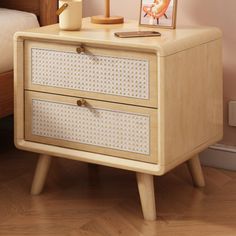 a wooden night stand with two drawers and a lamp on it next to a bed