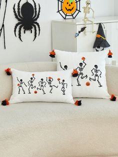 two halloween pillows on a couch with decorations in the background