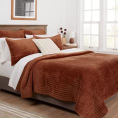 a bed with a brown comforter and white pillows