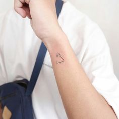 a person with a small triangle tattoo on their arm and wrist, holding onto a blue bag