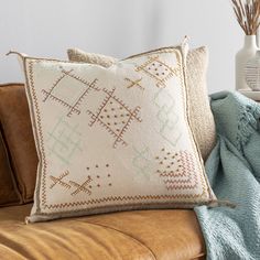 a brown couch with two pillows on top of it and a blue throw pillow next to it