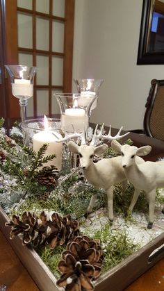 a tray with candles, pine cones and deer figurines