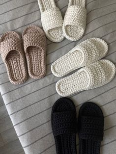 four crocheted slippers laid out on top of a bed next to each other