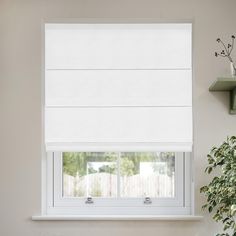 a window with white roman blinds in a room next to a potted green plant