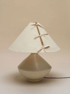 a lamp with a white shade on it and a black cord attached to the base