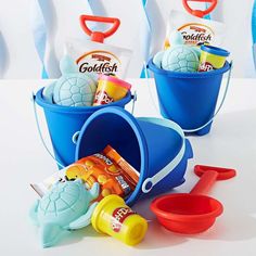 three buckets filled with toys on top of a white table next to each other