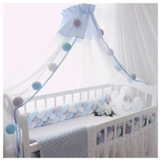 a baby crib with blue and white decorations on the top, along with a teddy bear