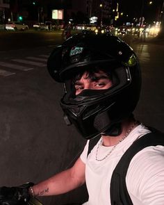 a young man wearing a helmet and holding onto his motorcycle's handlebars