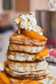 a stack of pancakes topped with whipped cream and peaches