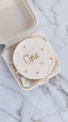 a cake in a white box with the word one on it's side and gold stars