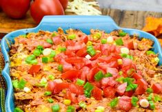 a blue casserole dish with tomatoes and green onions